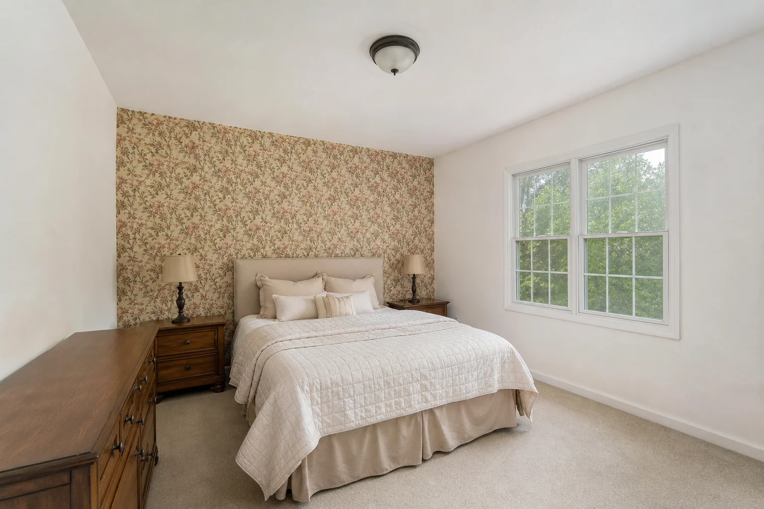 A plain room with a single patterned accent wall behind the bed and three flat white walls, looking dated and unbalanced